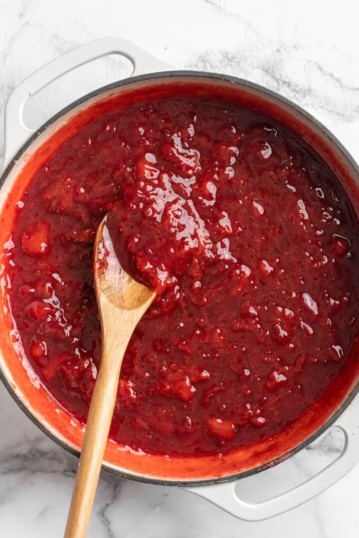 Strawberry jam in pot with wooden spoon