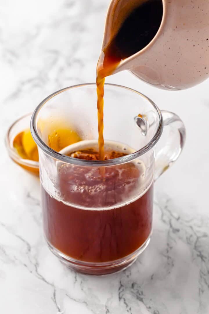 Pouring coffee into mug of black tea