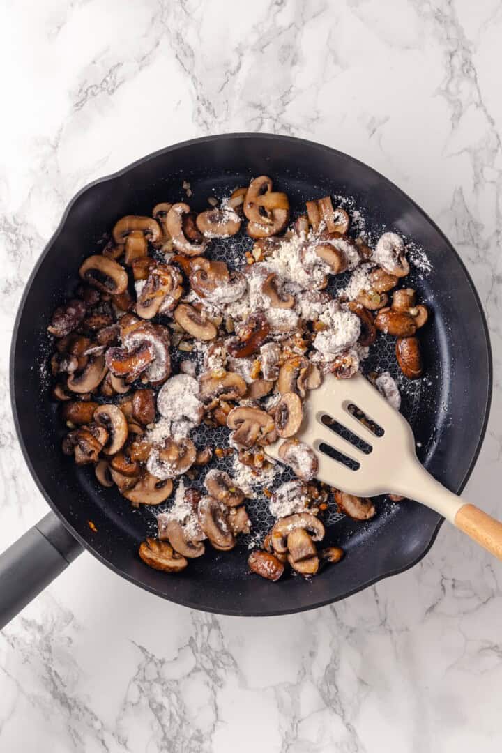 Flour added to mushrooms in skillet