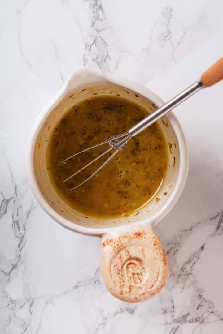 Small bowl with dressing for orzo salad with whisk