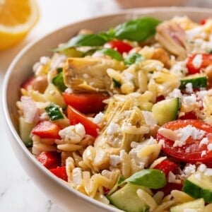 Closeup of orzo pasta salad with vegan feta and vegetables