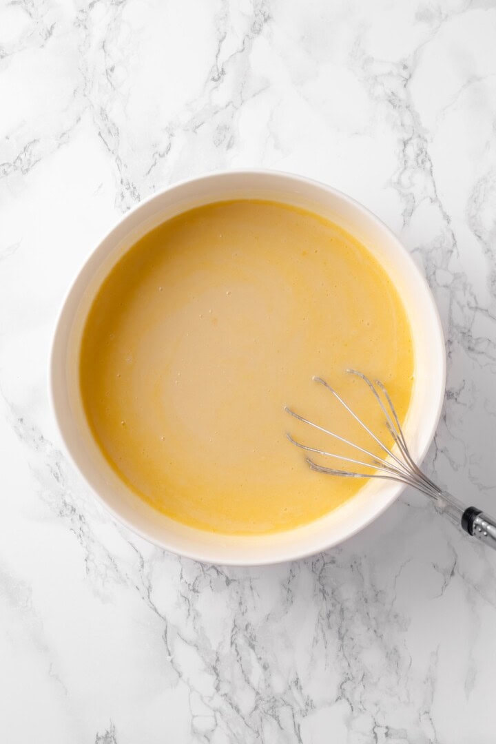 This moist and fluffy vegan chocolate chip muffin recipe is made with simple ingredients and easy enough that you can whip it up in minutes! Overhead view of wet ingredients for chocolate chip muffins in bowl with whisk