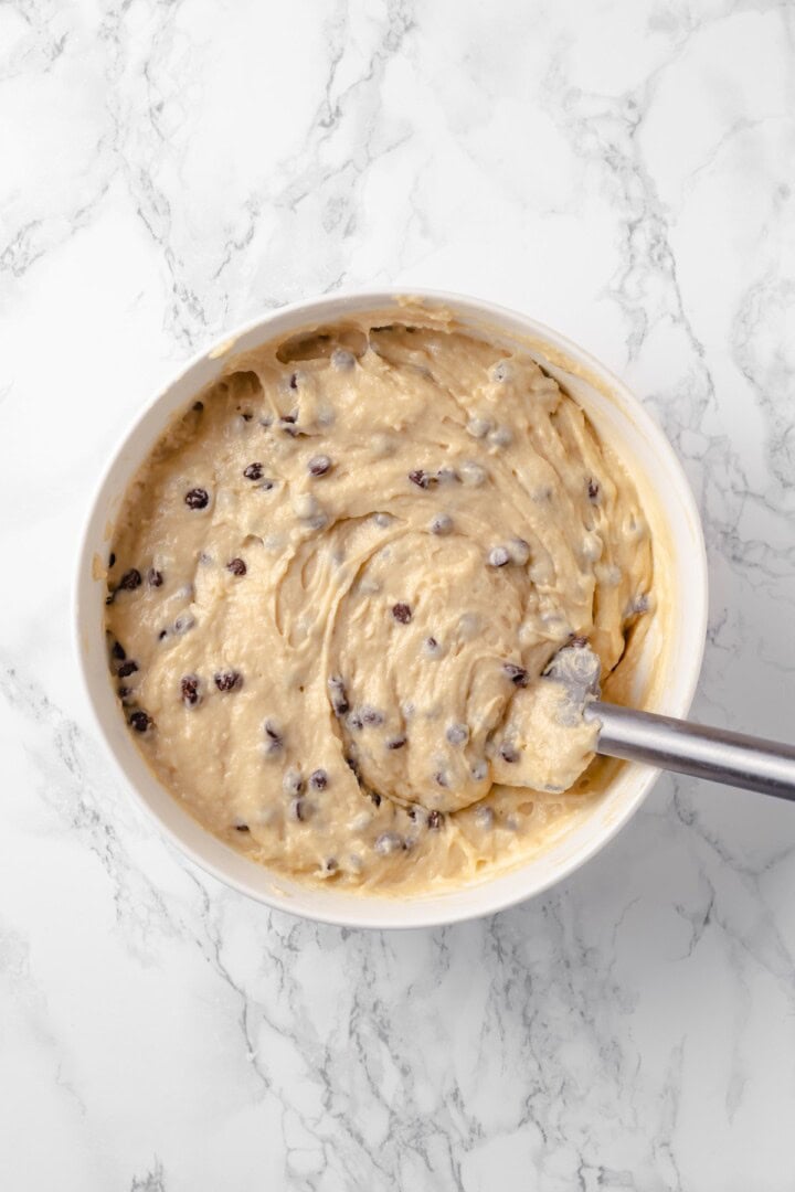 This moist and fluffy vegan chocolate chip muffin recipe is made with simple ingredients and easy enough that you can whip it up in minutes! Overhead view of chocolate chip muffin batter being stirred in bowl