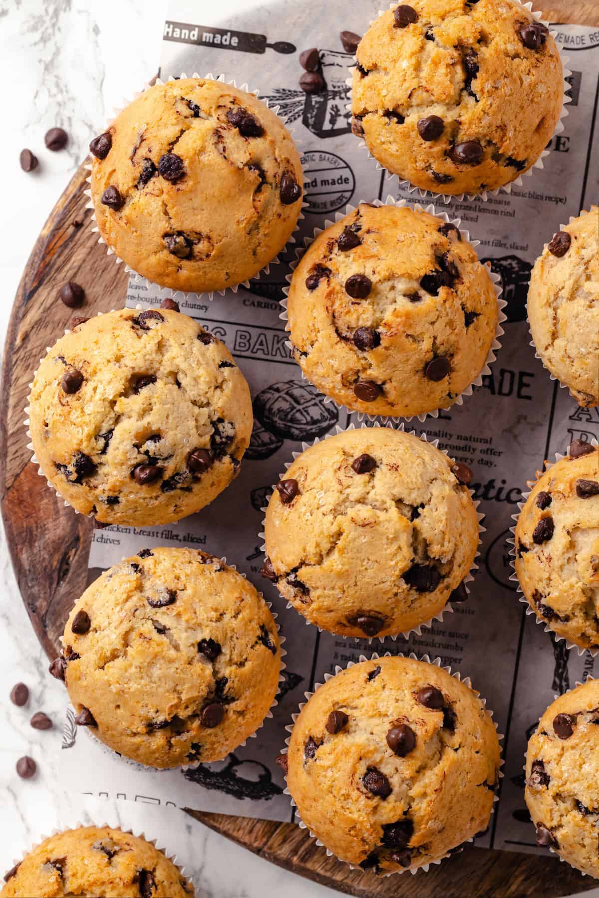 This moist and fluffy vegan chocolate chip muffin recipe is made with simple ingredients and easy enough that you can whip it up in minutes! Overhead view of vegan chocolate chip muffins on wood board