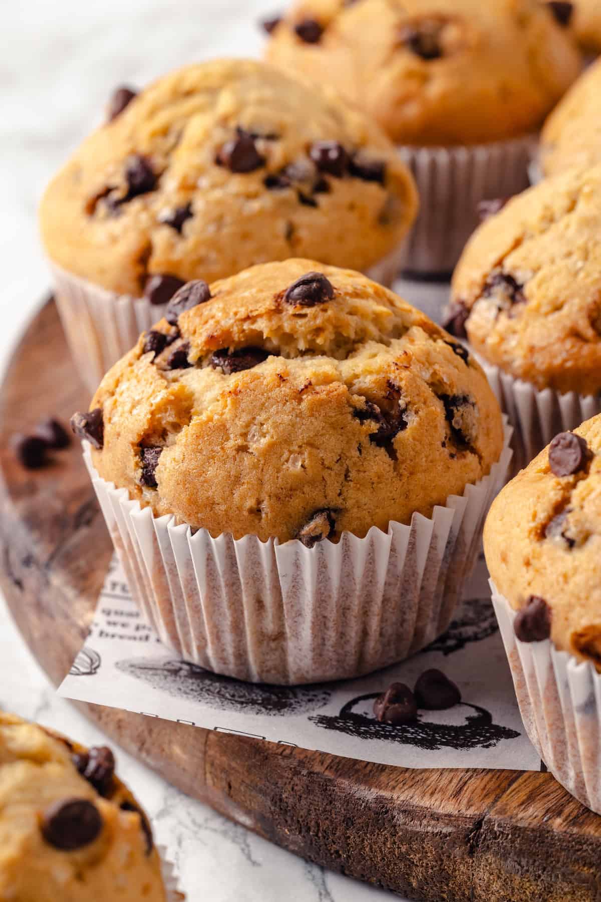 This moist and fluffy vegan chocolate chip muffin recipe is made with simple ingredients and easy enough that you can whip it up in minutes! Fluffy vegan chocolate chip muffins on wood board