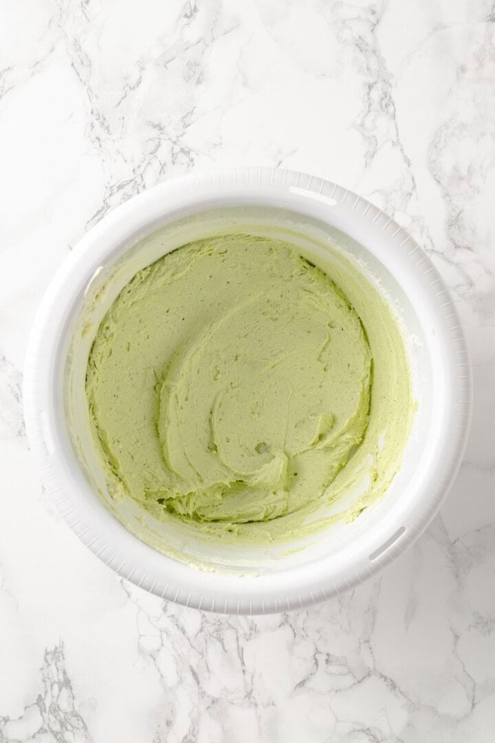 Overhead view of pistachio frosting in mixing bowl before adding powdered sugar