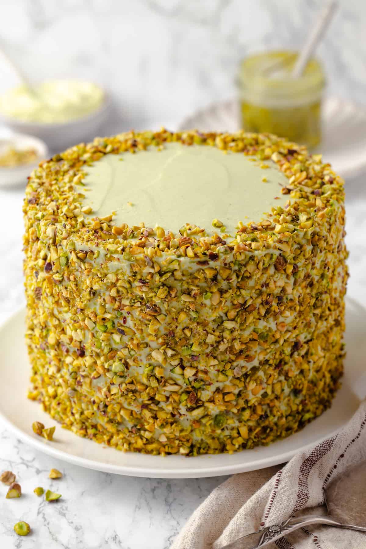 Whole pistachio cake on platter before slicing