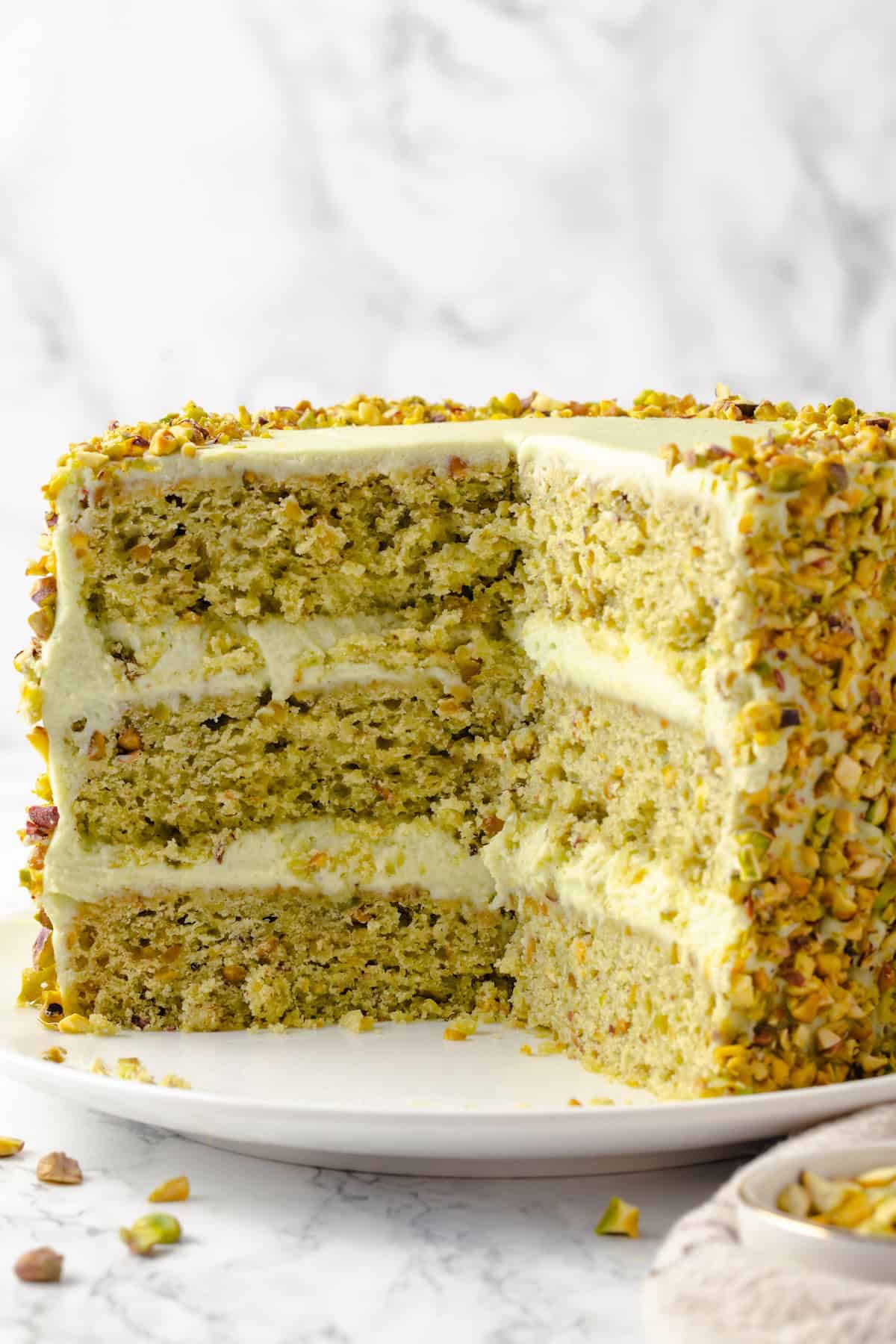 Vegan pistachio cake on plate with slices removed to show layers