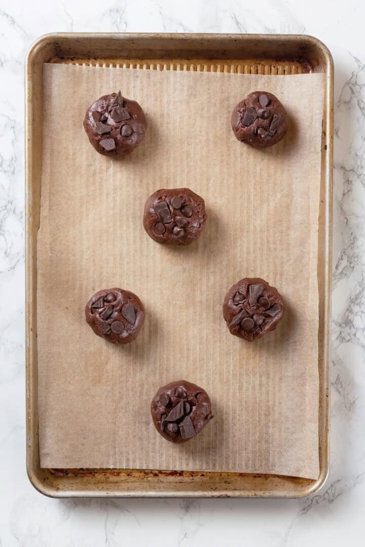 Overhead view of double chocolate chunk cookie dough on parchment-lined baking sheet
