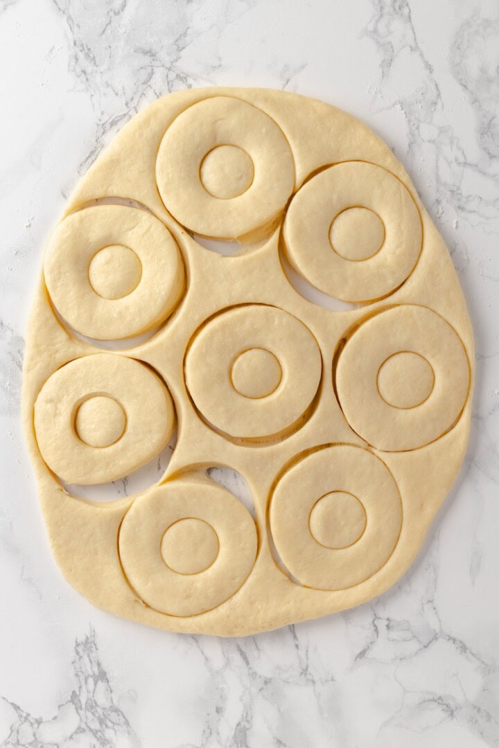 Overhead view of cut donut dough on marble work surface