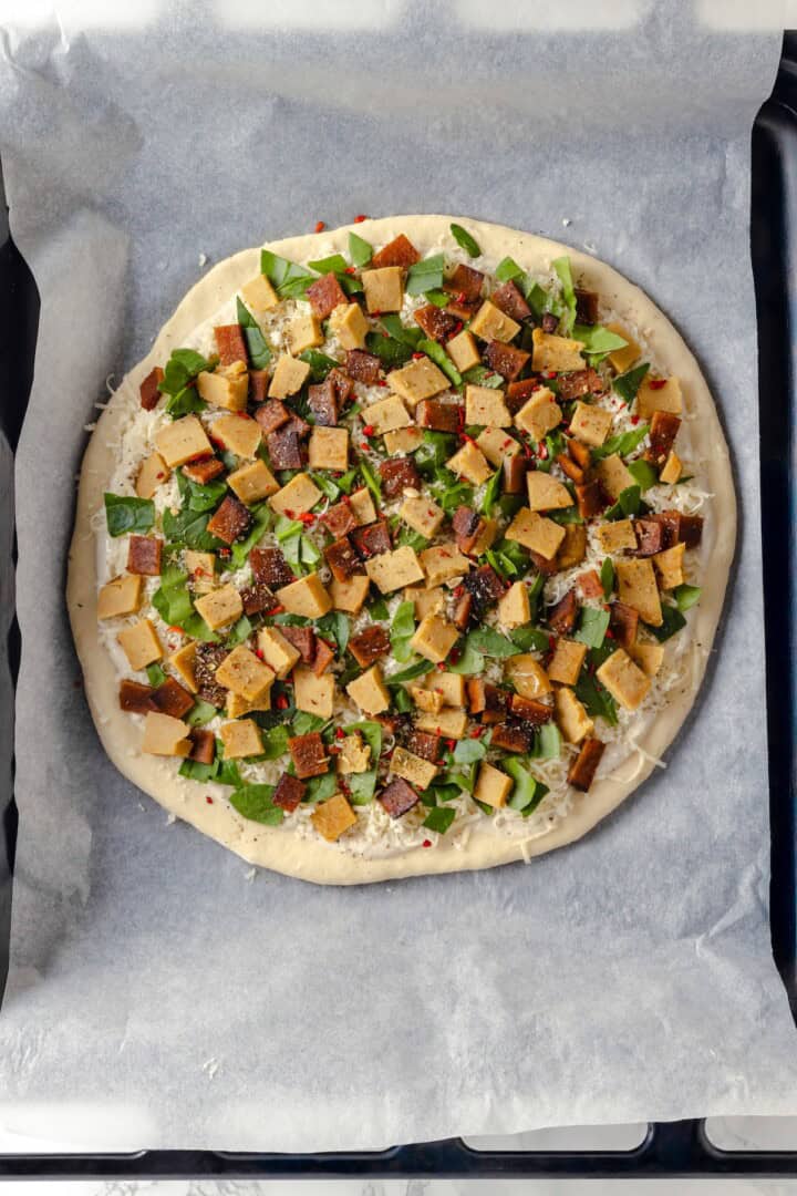 Overhead view of unbaked Alfredo sauce pizza on pan