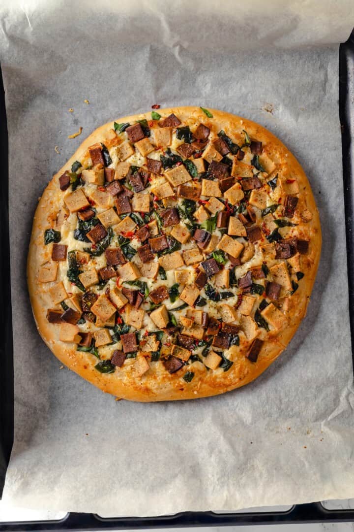 Overhead view of Alfredo sauce pizza on parchment-lined pan