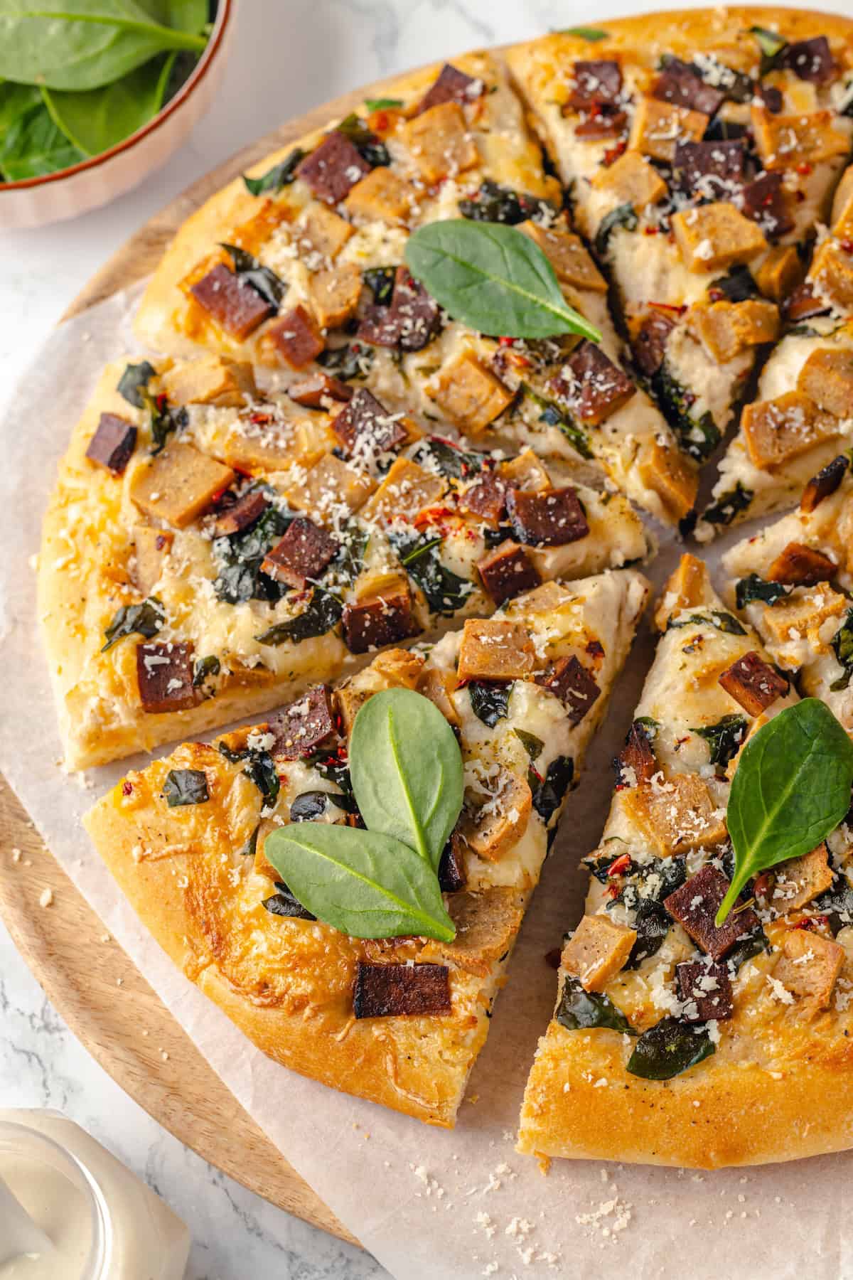 Sliced Alfredo sauce pizza on parchment paper