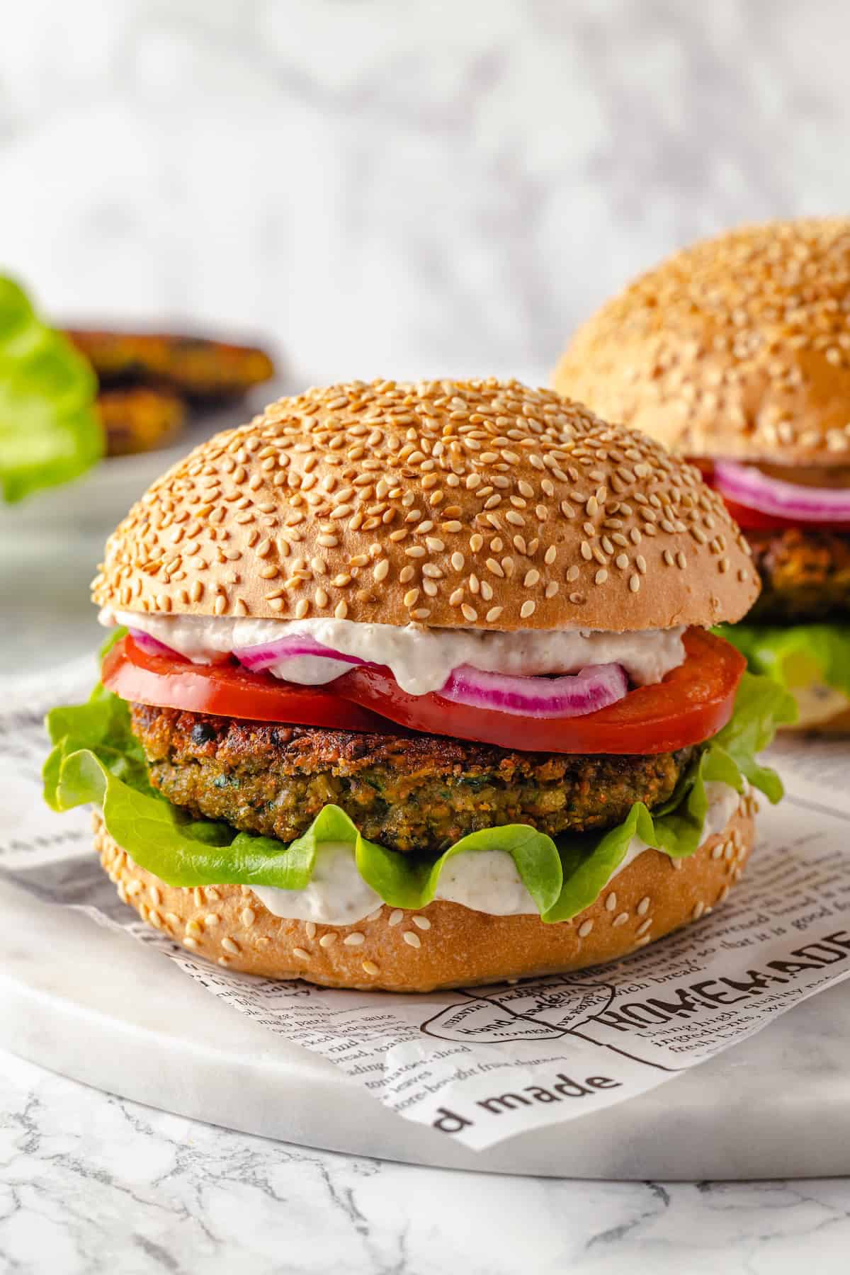 Two vegan falafel burgers on sesame seed buns