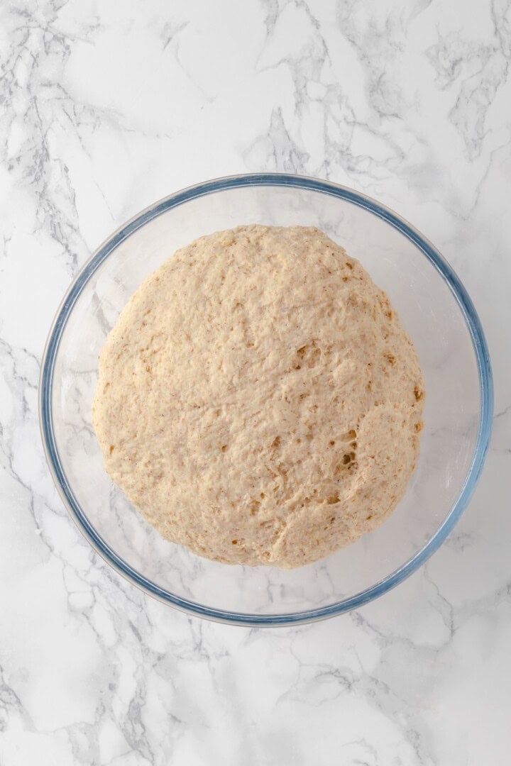 Overhead view of bagel dough in glass bowl after rising