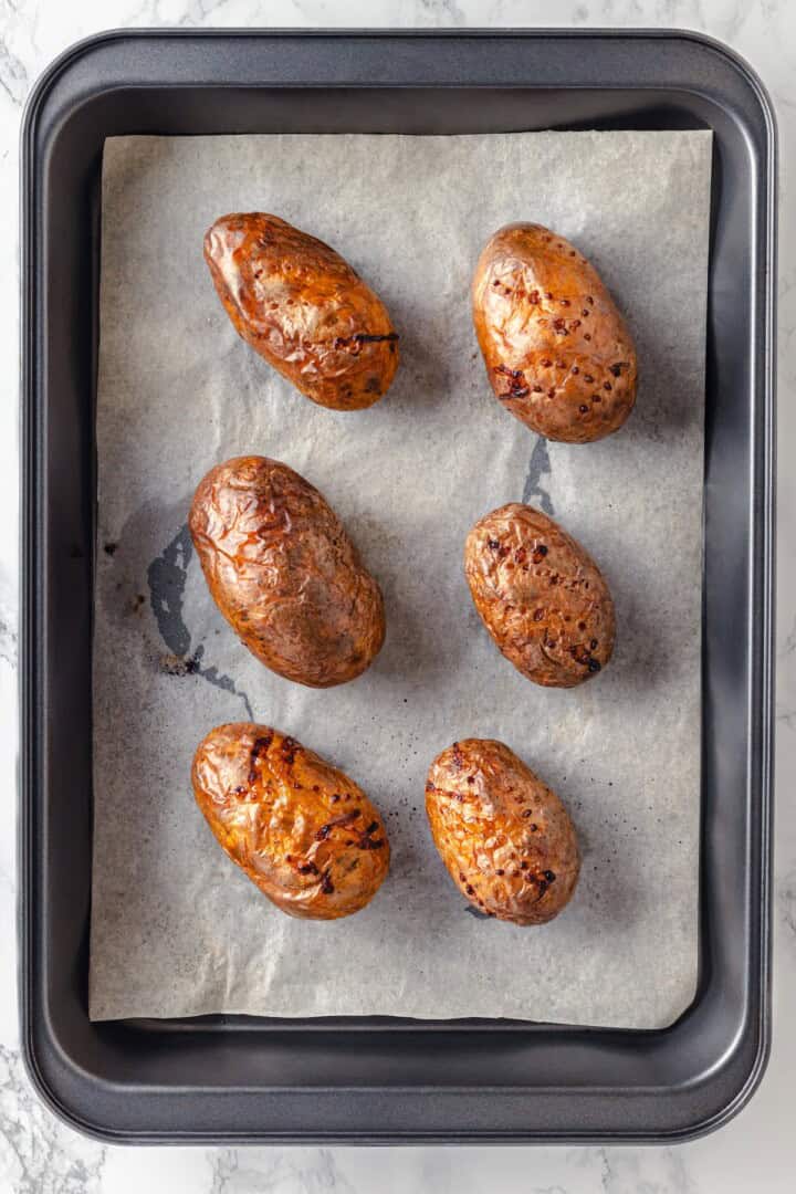 Overhead view of baked potatoes on parchment-lined sheet pan