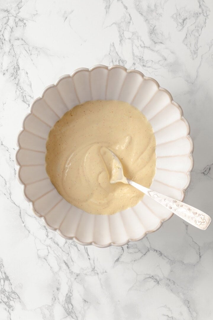 Overhead view of dressing for potato salad in bowl with spoon