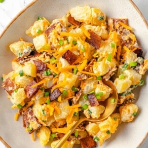 Overhead view of vegan loaded baked potato salad in bowl with spoon