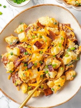 Overhead view of vegan loaded baked potato salad in bowl with spoon