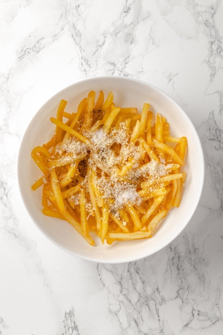 Vegan Parmesan added to bowl of truffle fries