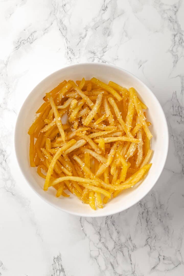 Overhead view of truffle fries in bowl with vegan Parmesan