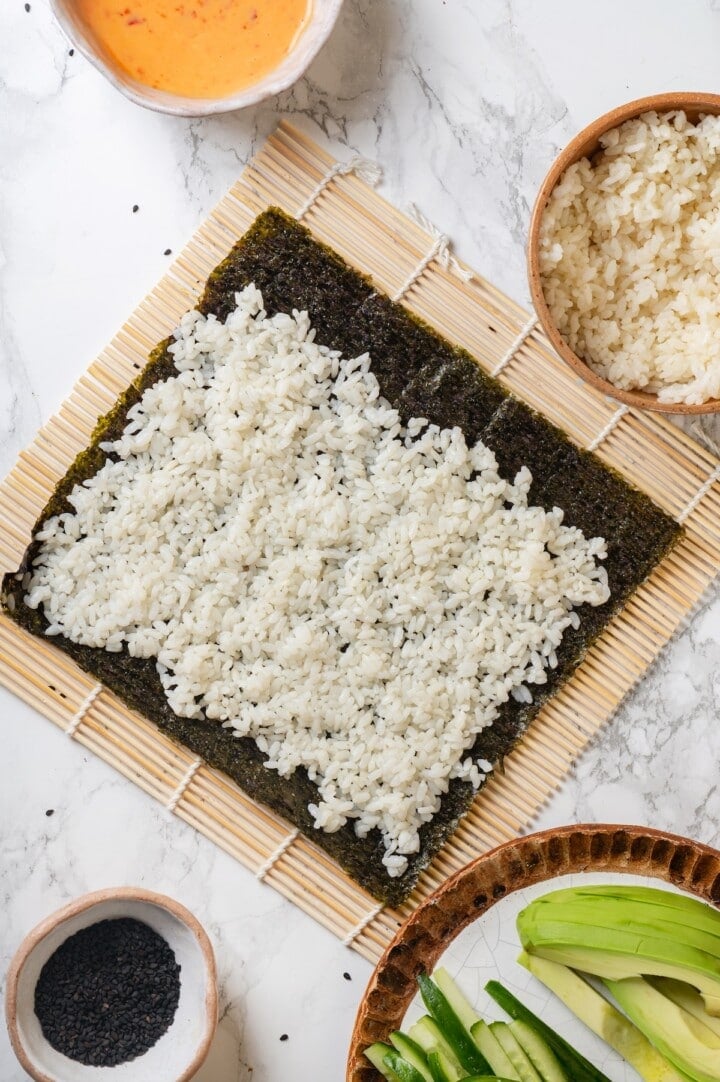 Overhead view of sushi rice on sheet of nori