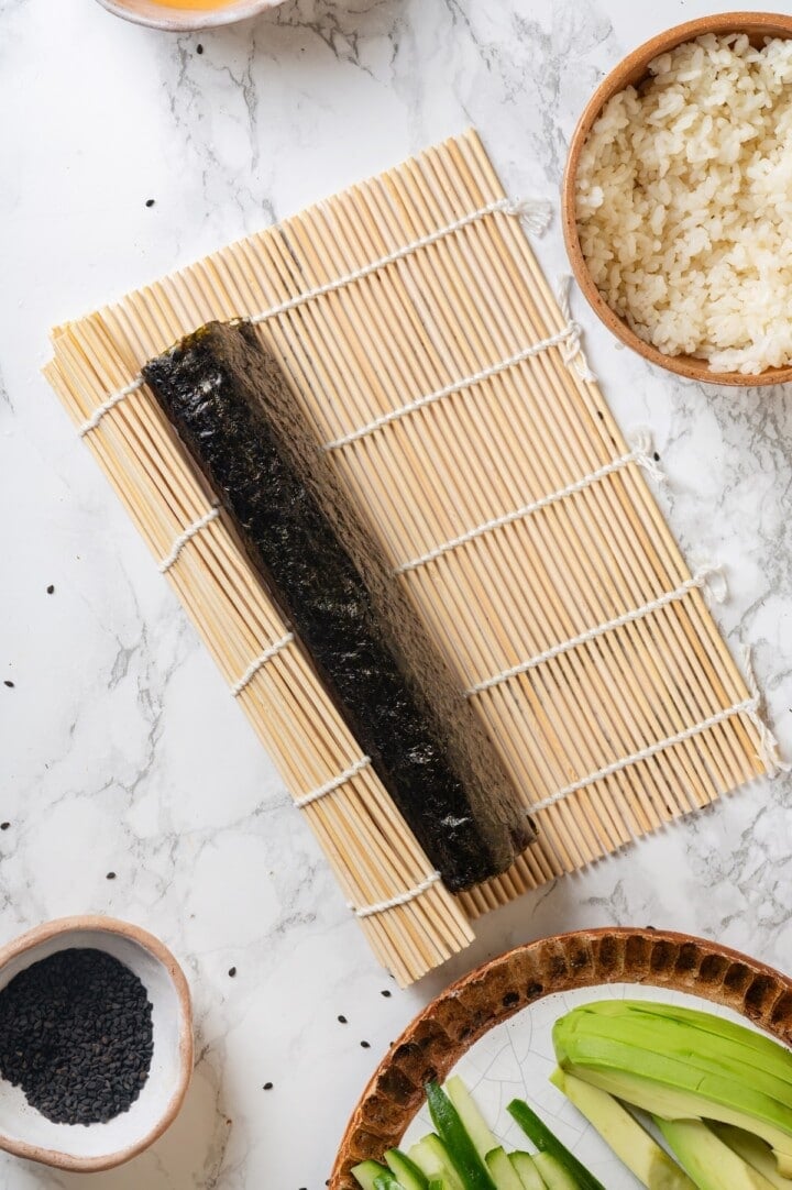 Rolled up avocado sushi on bamboo mat