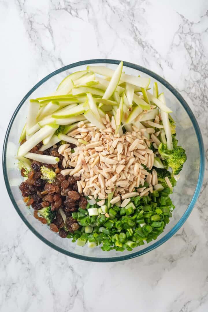 Overhead view of ingredients for broccoli slaw in bowl before tossing