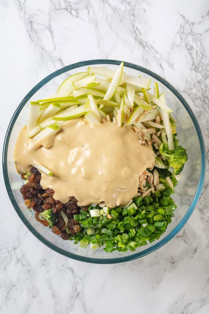 Overhead view of broccoli slaw ingredients in bowl before tossing