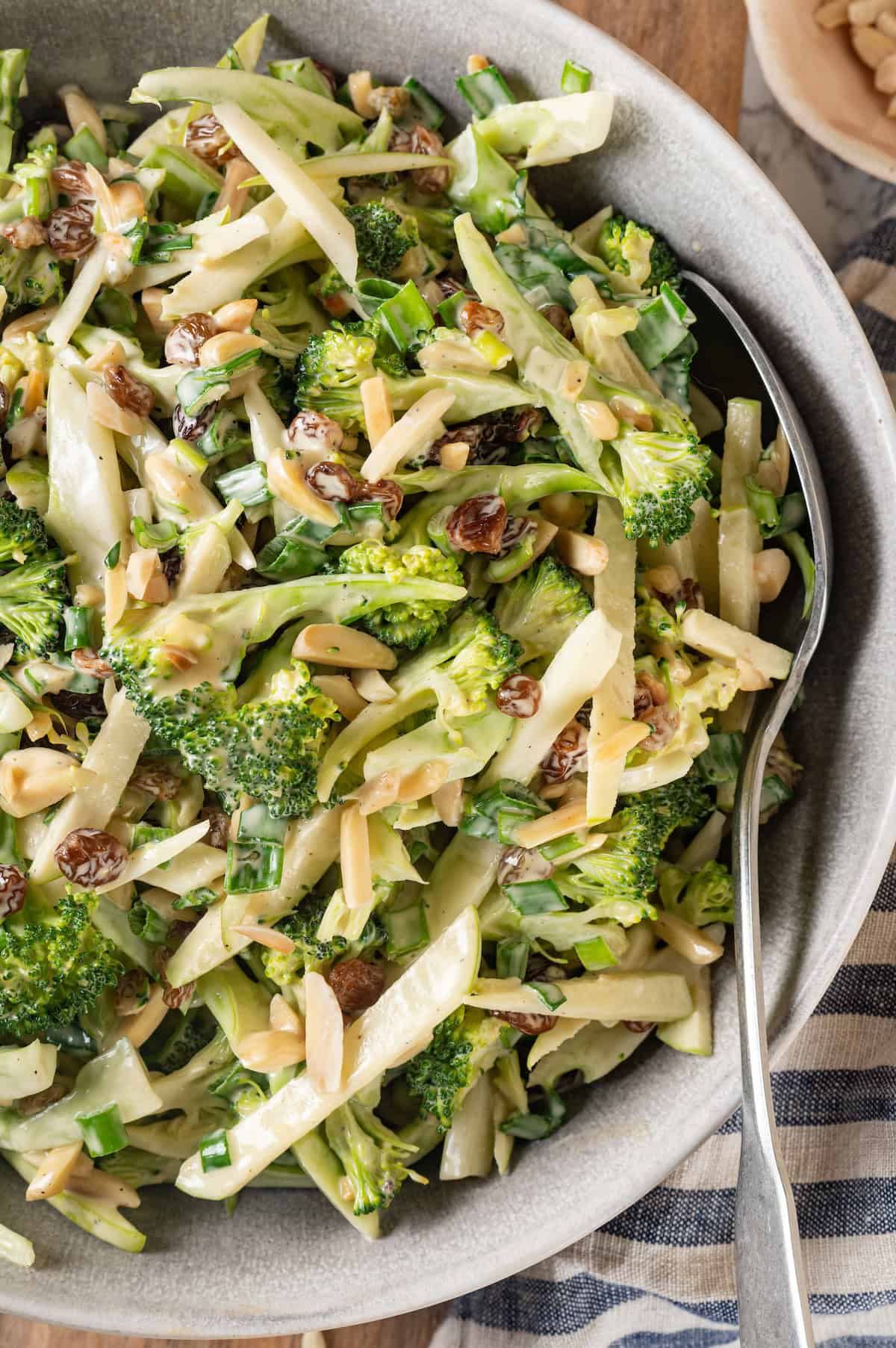 Overhead view of broccoli slaw in serving bowl with spoon