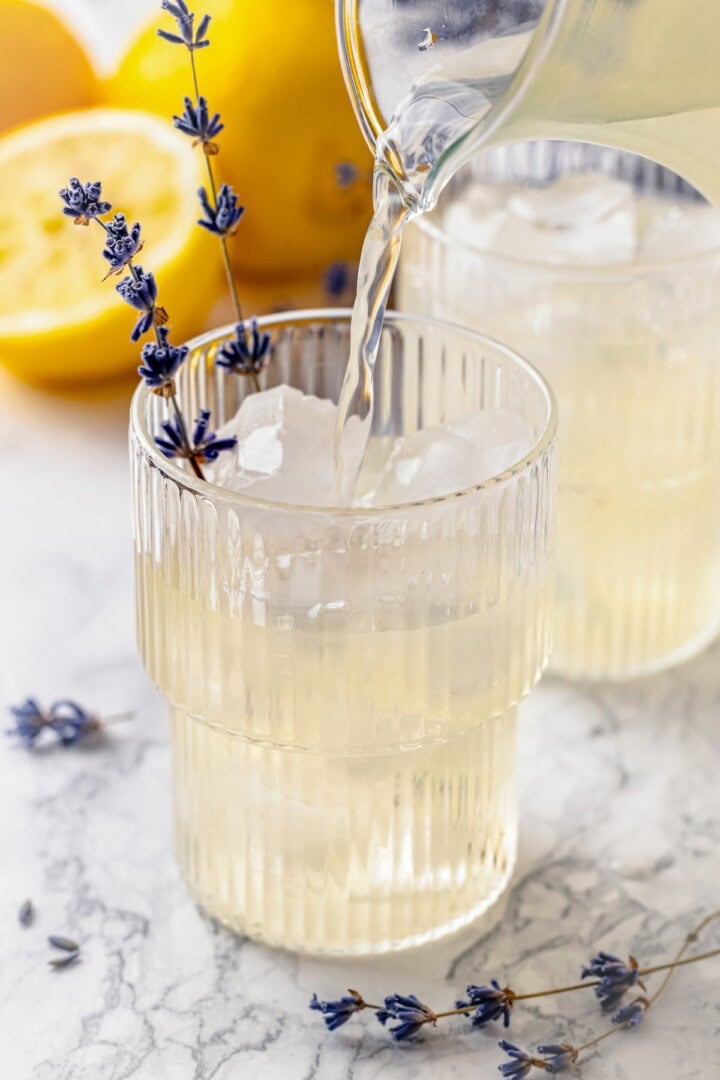 Pouring lavender lemonade into glass with ice