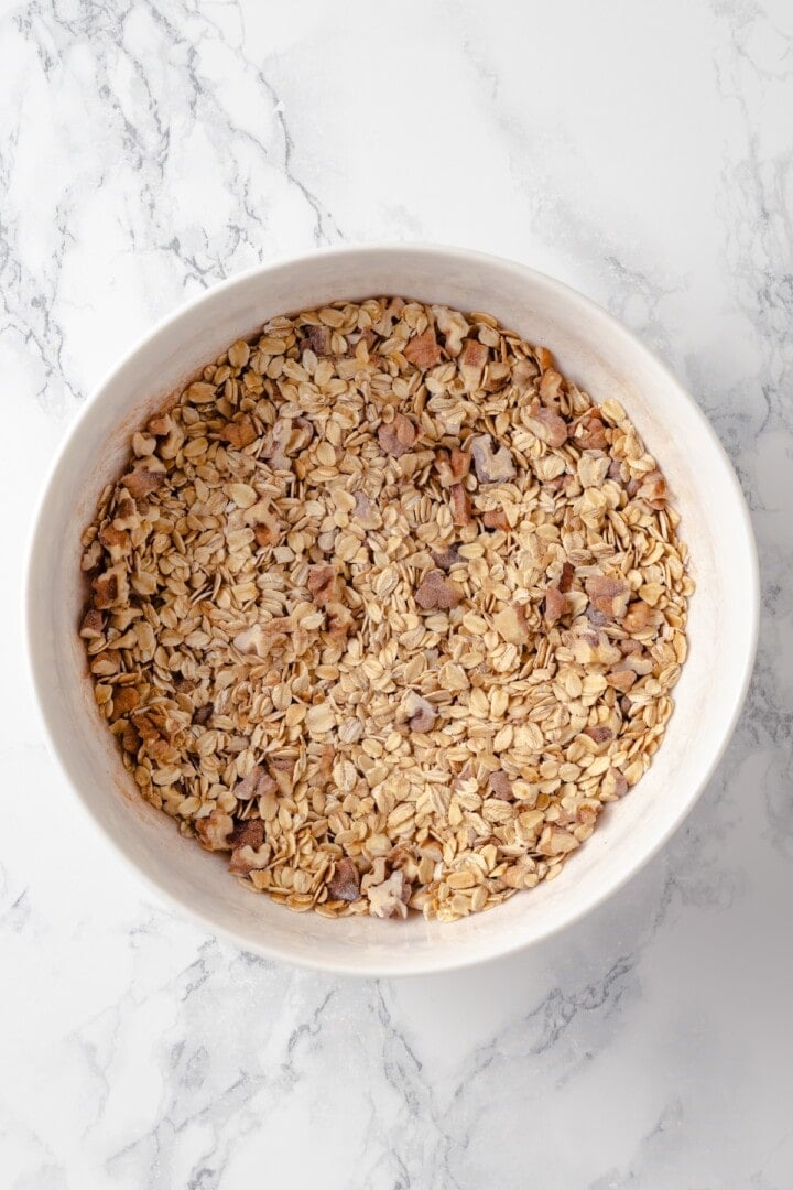 Overhead view of oats, walnuts, and dry ingredients mixed in bowl for baked oatmeal