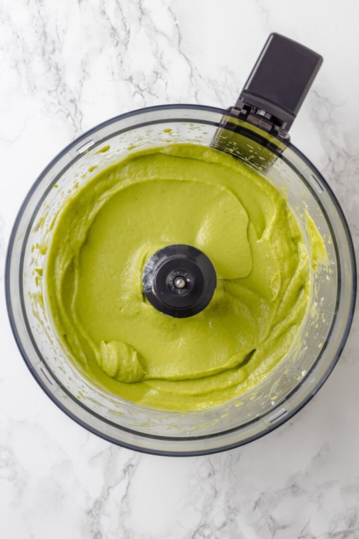 Overhead view of pureed avocado mixture in food processor bowl