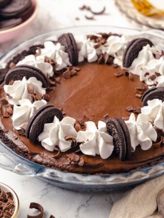 Whole chocolate mousse pie in glass pie plate with Oreos and whipped cream for garnish