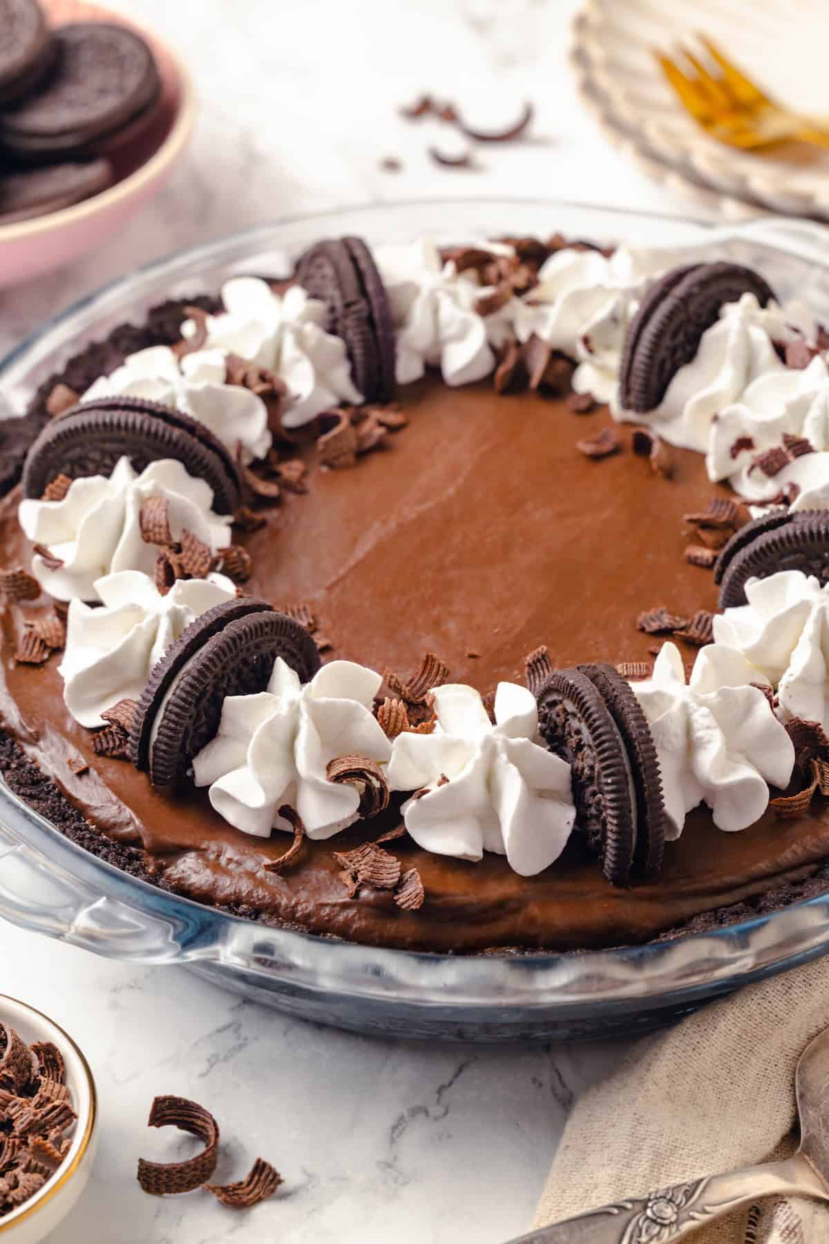 With an Oreo crust, decadent vegan mousse filling, and coconut whipped cream, this chocolate mousse pie recipe is absolutely irresistible! Whole chocolate mousse pie in glass pie plate with Oreos and whipped cream for garnish