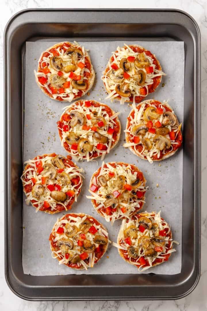 Overhead view of English muffin pizzas on baking sheet before baking