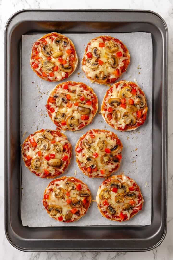Overhead view of English muffin pizzas on baking sheet