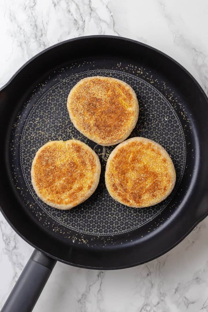 Overhead view of English muffins cooking in skillet