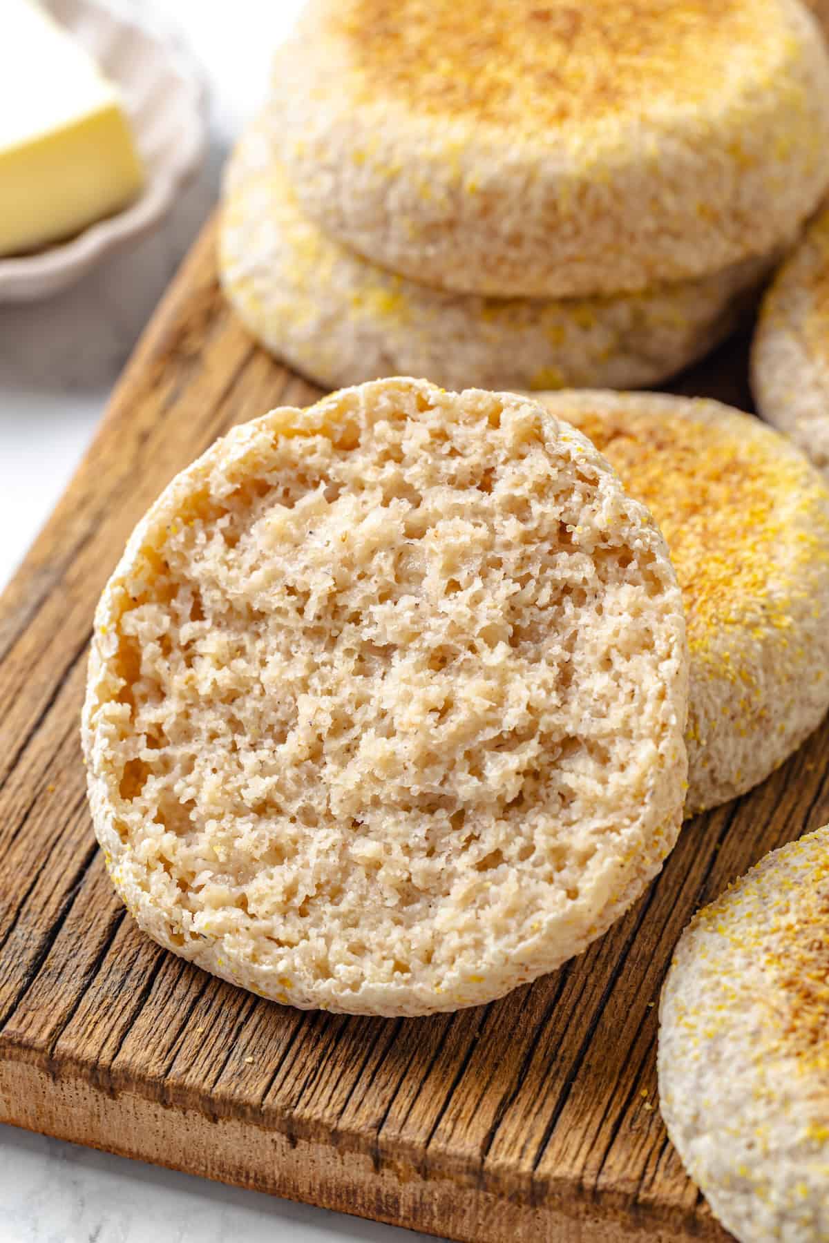 Sliced gluten-free English muffin half on cutting board with additional muffins