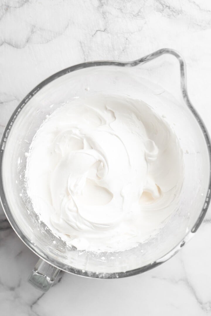 Overhead view of aquafaba mixture in glass mixing bowl before adding butter and vanilla