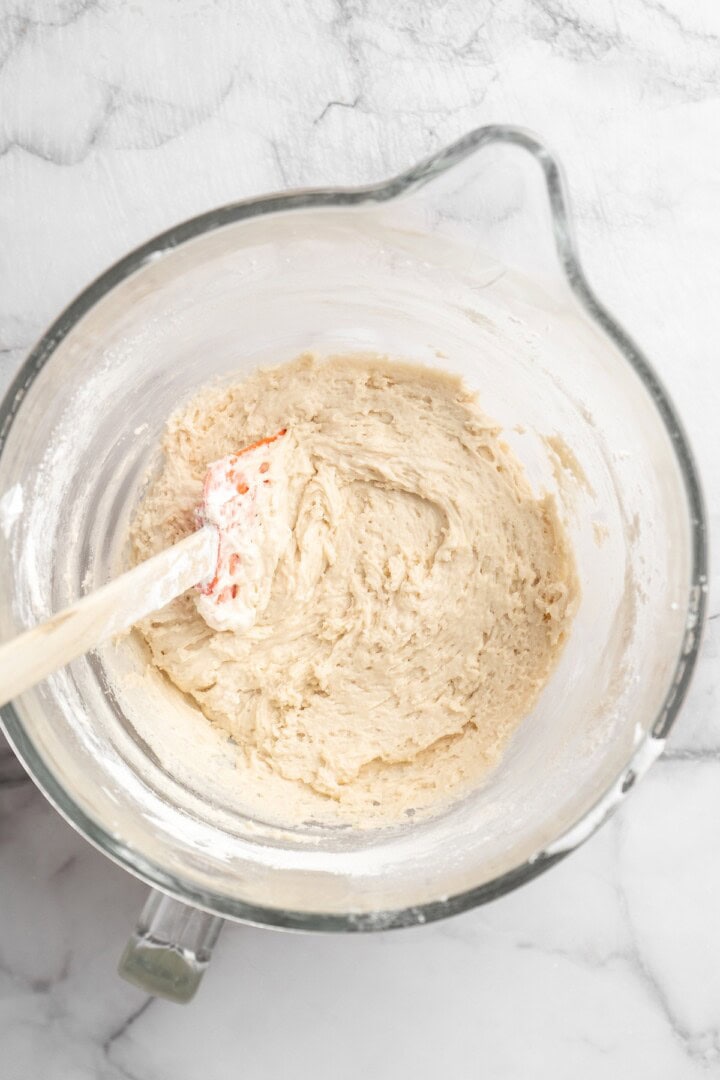 Overhead view of vegan ladyfinger batter in glass mixing bowl with rubber spatula