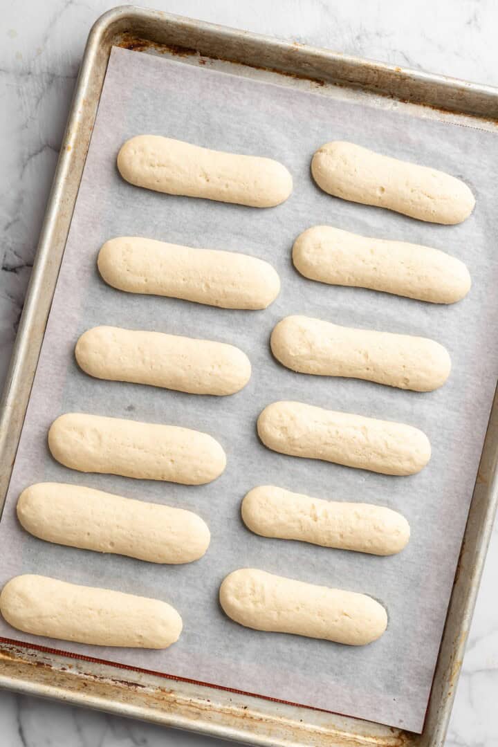 Overhead view of vegan ladyfingers on parchment-lined baking sheet