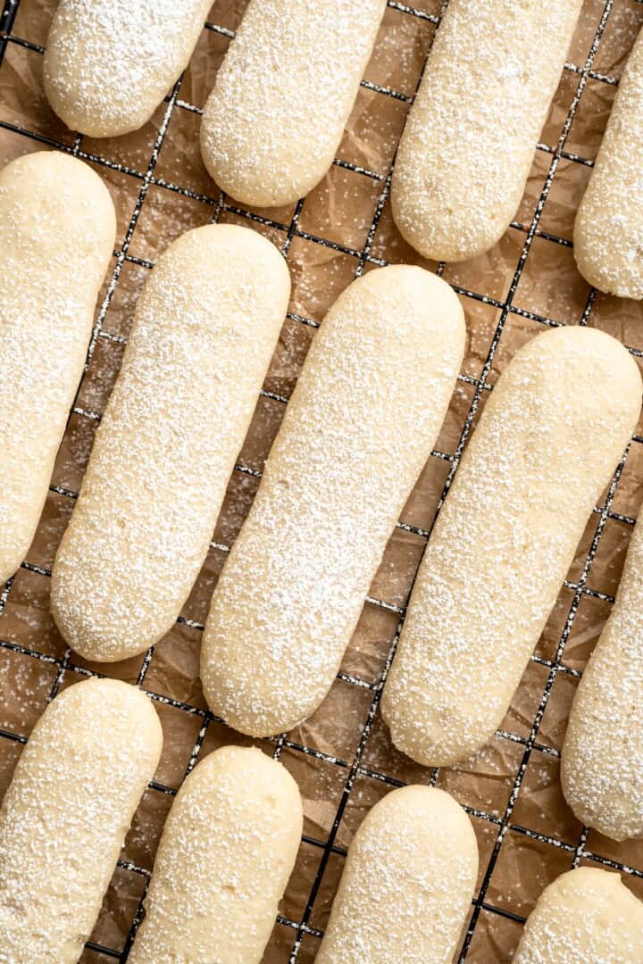 Overhead view of vegan ladyfingers on wire rack with dusting of powdered sugar