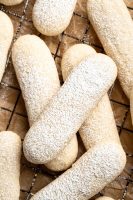 Overhead view of vegan ladyfingers on wire rack, with dusting of powdered sugar