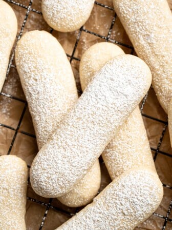 Overhead view of vegan ladyfingers on wire rack, with dusting of powdered sugar