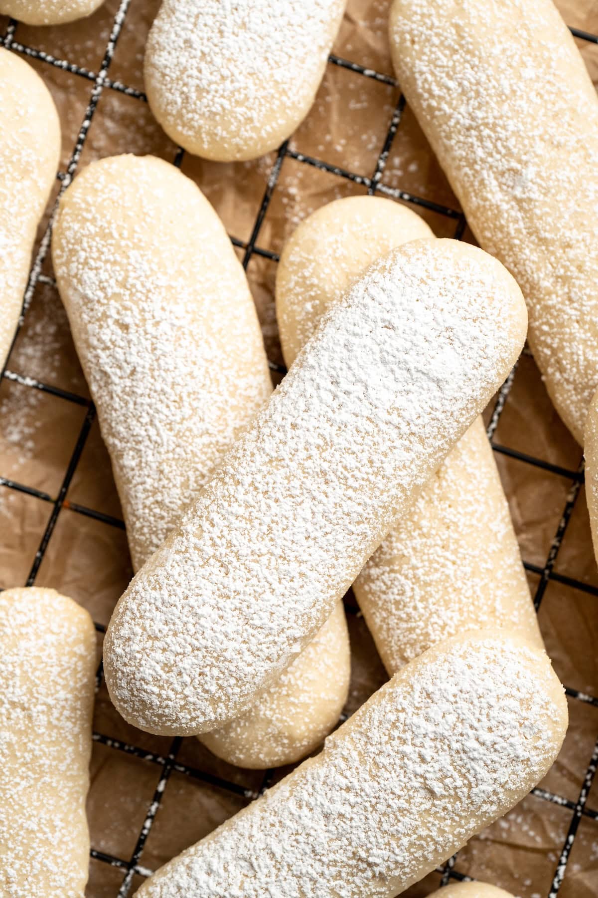 These vegan ladyfingers have the same texture and flavour as the traditional version, but they’re made without the eggs thanks to aquafaba! Overhead view of vegan ladyfingers on wire rack, with dusting of powdered sugar
