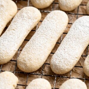 Powdered sugar dusted vegan ladyfingers on cooling rack