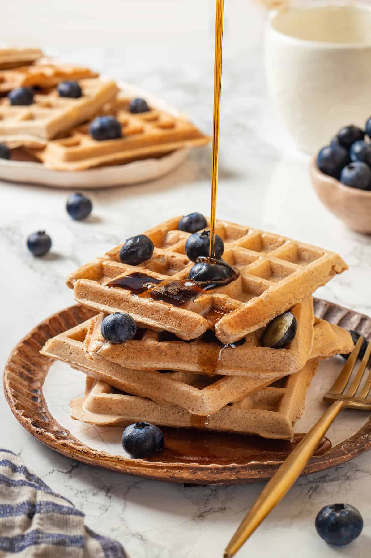 Pouring syrup onto stack of protein waffles