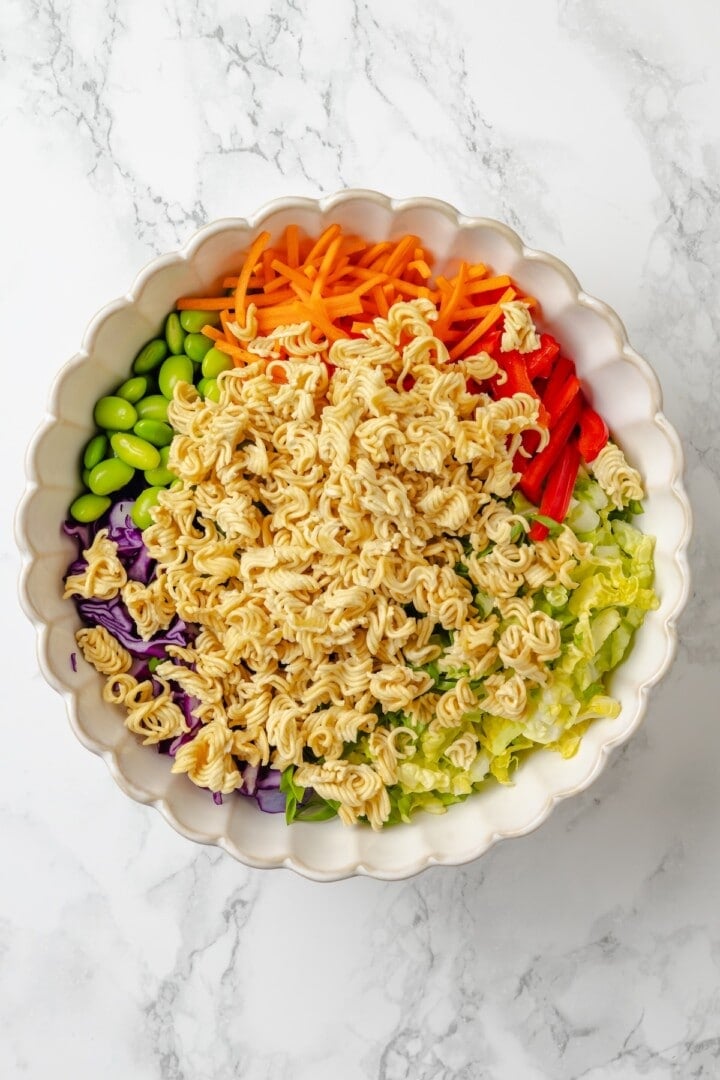 Overhead view of ingredients for ramen noodle salad in bowl before tossing