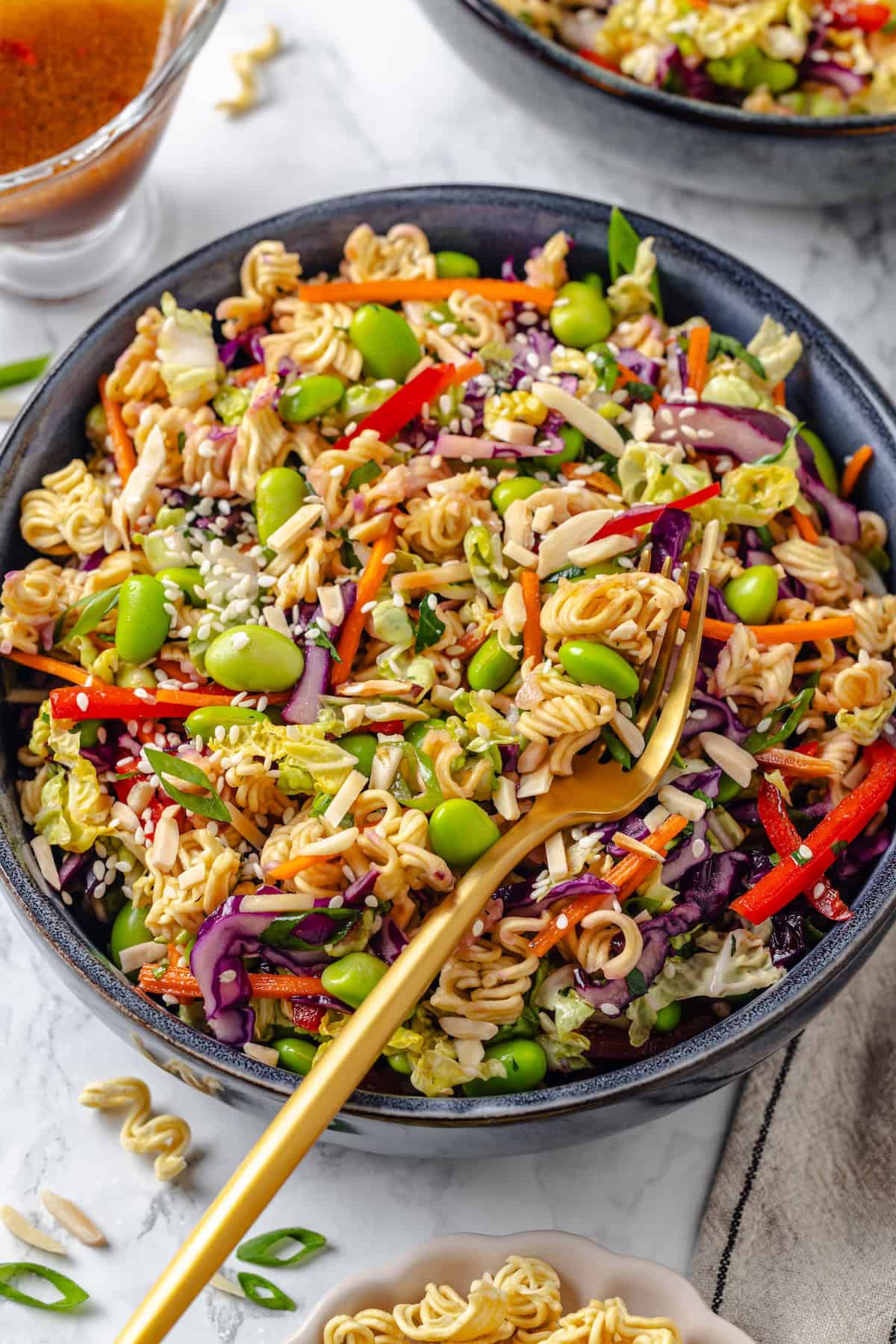 With crunchy noodles, almonds, cabbage and tender edamame in a zippy ginger dressing, this ramen noodle salad recipe is easy and delicious! Overhead view of ramen noodle salad in bowl with fork